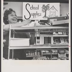 A salesclerk points to a sign promoting school supplies