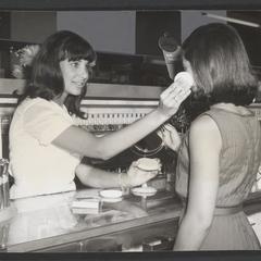 Cosmetic clerk teaches customer how to apply makeup