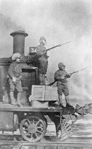 Three Japanese soldiers on a railway engine.