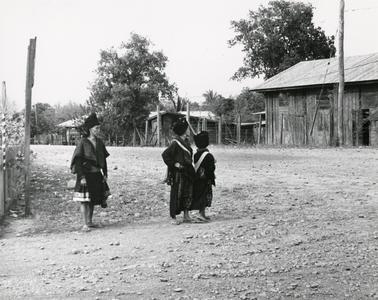 One Blue Hmong woman and two Yao women stand on a road in the town of Xaignabouri in Xaignabouri Province