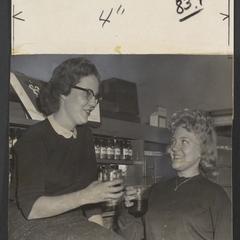Two women hold glass containers