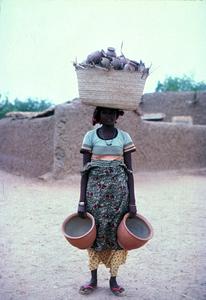 Hausa Potter Carries Her Pots to Kiln to be Fired