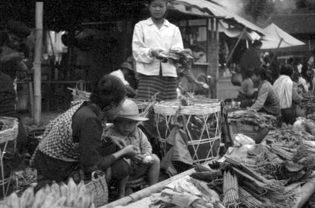 Basket of charcoal adjoining stalls of vegetable products, Lao women vendors