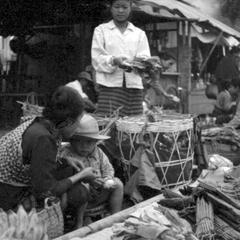 Basket of charcoal adjoining stalls of vegetable products, Lao women vendors