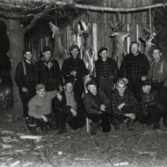 Group of hunters with deer hanging from pole
