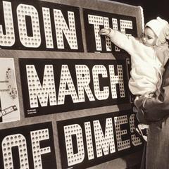 Mother and daughter add a dime to a March of Dimes fundraising bulletin board in Milwaukee, Wisconsin