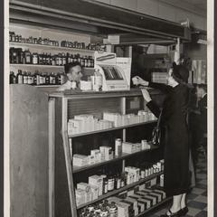 A pharmacist assists a customer at the prescription counter