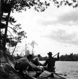 Nina, Bergere Kenney, and Luna with canoes on shore at Quetico