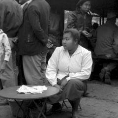 Lao woman selling lottery tickets at the edge of a group of men standing around