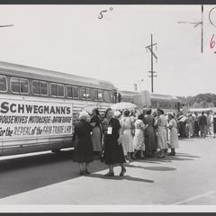 Women stand in line to board a bus in a motorcade