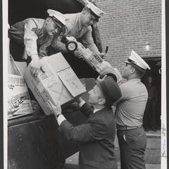 Several men unload boxes of toys from a truck
