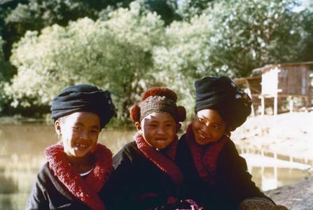Three Yao (Iu Mien) girls are seated near a pond at in Houa Khong Province