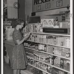 A young woman selects items from a drugstore display