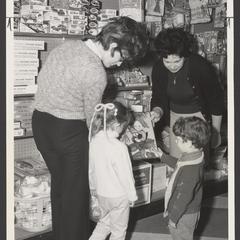 Two women help two young children select toys
