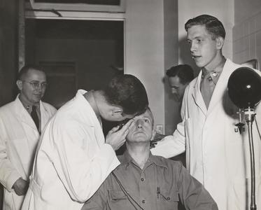 Medical students examine man's eye