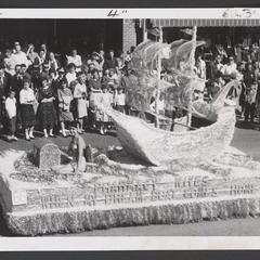 A woman in a bathing suit sits on a decorated float in a parade