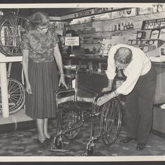 A salesclerk demonstrates wheelchair features for a customer