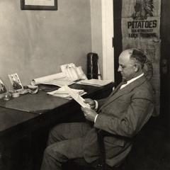 James G. Milward at desk, potato sack in background