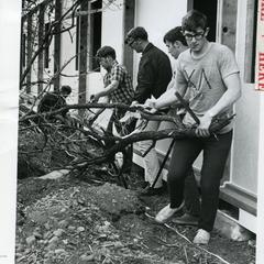 Interfraternity Council members help remove brush from the area around the Modulux to ready it for the fall semester