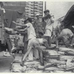 Filipinos unload sugar from trucks, Manila, 1945