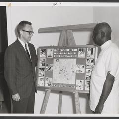 Two men look at a map on a board for Operation Lift