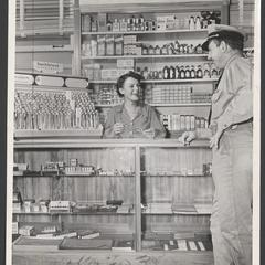 A woman helps a serviceman at a drugstore counter
