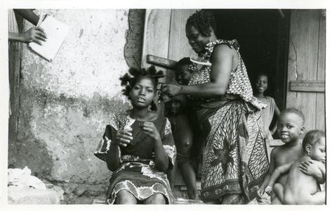 A woman plaits a young girl's hair