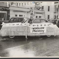 Woman drives a car decorated as a parade float for Winslow Pharmacy