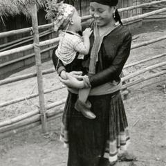 A Blue Hmong (Hmong Njua) mother holds her crying child in a Hmong village in the vicinity of Muang Vang Vieng in Vientiane Province