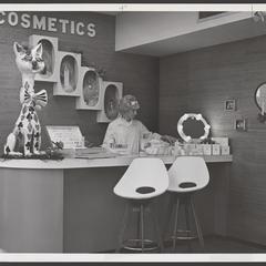 A saleswoman stands behind a cosmetics counter