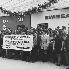 Students at airport with sign for European Seminar class
