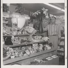 A salesman adjusts a gift display in a drugstore