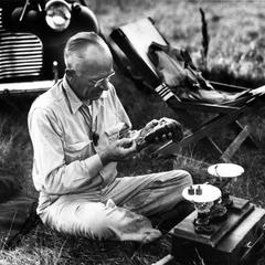 After the woodcock hunt, weighing specimens, AL seated with scale, 1946