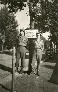 Two GIs posing next to the Company I, 120th Infantry sign
