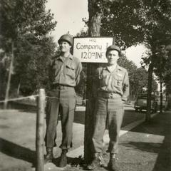 Two GIs posing next to the Company I, 120th Infantry sign