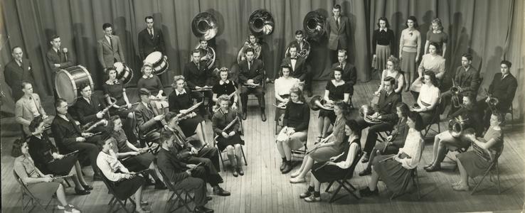 Stout Band group photograph, sitting in concert band formation on stage