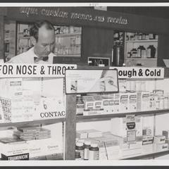 Pharmacist busy working behind the drugstore cough and cold section