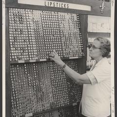 A salesclerk examines a honeycomb lipstick display