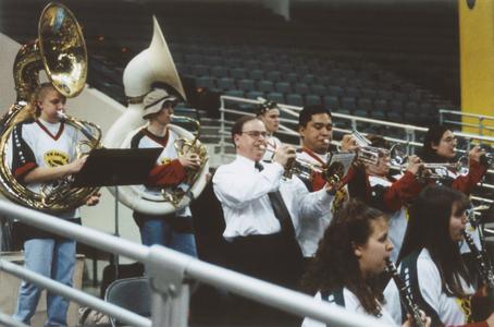 Chancellor Mark L. Perkins playing the trumpet with the pep band at a women's basketball game