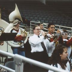 Chancellor Mark L. Perkins playing the trumpet with the pep band at a women's basketball game