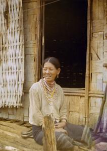 A Nyaheun woman is seated on the porch of her dwelling in Attapu Province
