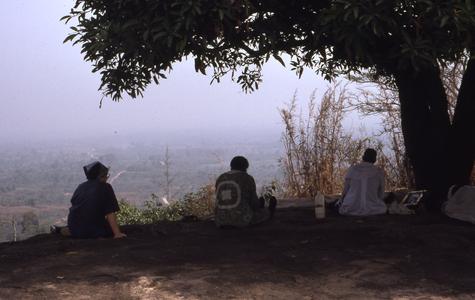 Three people sitting on hill