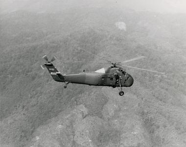 A H-34 helicopter flies over the mountains in Houa Khong Province