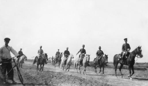 An American soldier accompanied by Chinese military personnel on horseback.