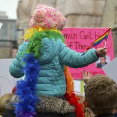 Kid waiving rainbow flag on shoulders