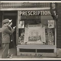 A man and a woman look at a pharmacy window display