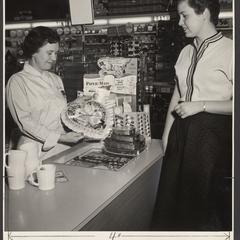 A saleswoman displays a box of Valentine's chocolates for a customer