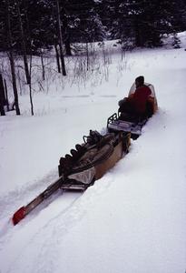 Bill Tonn on a snowmobile towing a sled