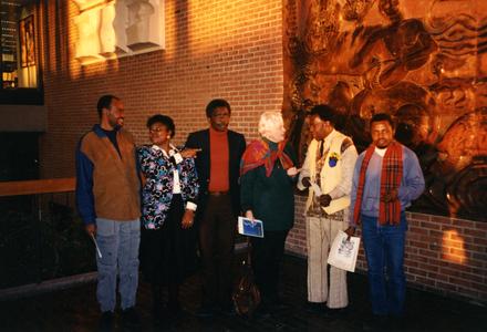 Photo of Folarin and others in front of mural