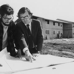 Two men looking at blueprints in front of the Bay Apartments